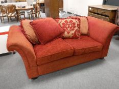 A two seater settee with loose cushions in red fabric