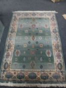 A contemporary fringed woollen rug on green ground