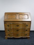 An early 20th century oak serpentine fronted bureau