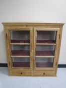 A stripped pine glazed door wall cabinet