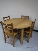 A circular oak dining table and four pine ladder back chairs