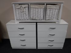 A pair of white four drawer chests and a storage unit with wicker baskets