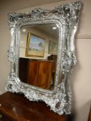 A very ornate silvered overmantel mirror,