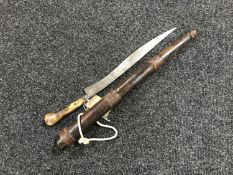 An Indonesian curved knife in carved hardwood sheath CONDITION REPORT: Blade pitted