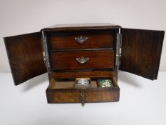 An Edwardian oak double door smoker's cabinet fitted with three drawers