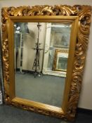 A bevelled overmantel mirror in ornate gilded frame,