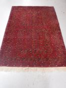 An Afghan fringed carpet on red ground,