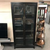 A glazed ebonised double door display cabinet,