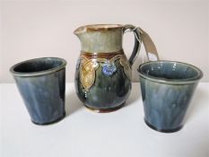 A Royal Doulton Lambeth jug, height 12 cm and a pair of Royal Doulton Lambeth beakers, height 7.
