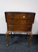 A walnut serpentine fronted flap sided three drawer chest