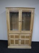 An Ercol elm glazed door bookcase fitted cupboards beneath