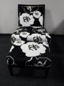 A chair with stool upholstered in a black and white floral fabric