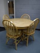 A circular beech effect pedestal kitchen table and four chairs