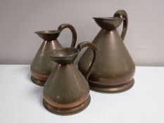 A set of three graduated copper jugs