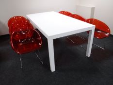 A contemporary white high gloss dining table and six red perspex bucket chairs