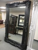 A very large bevelled ornate black framed mirror,