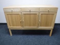 A mid 20th century blonde oak triple door sideboard