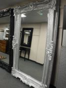 A very large bevelled ornate silvered framed mirror,