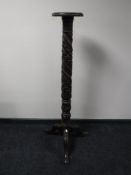 A carved mahogany torchere on three way pedestal