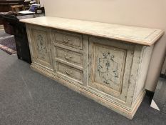 A painted cream sideboard fitted cupboards and drawers,