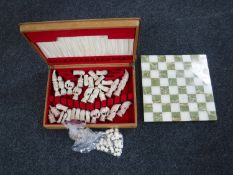 An onyx chess set with pieces together with an extra set of chess pieces and a cutlery canteen