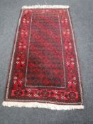 A fringed Afghan rug on red ground