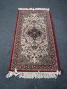 A machine made Keshan fringed rug on red ground