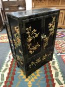 An Oriental lacquered and gilt double door low cabinet,