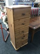 A narrow pine five drawer chest