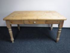 A pine farmhouse kitchen table fitted with a drawer