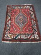 A fringed Persian Khamseh rug of geometric design on red ground