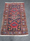 A fringed Kazak rug of geometric design on red ground
