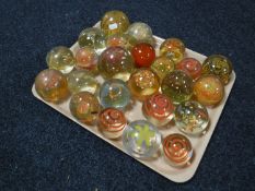 A tray of twenty four glass paperweights
