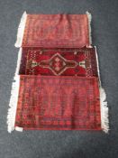 Three fringed Afghan rugs on red ground