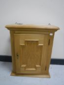 A blonde oak single door wall cabinet