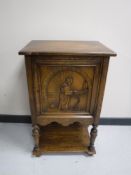 An oak single door cabinet with carved panel depicting a monk