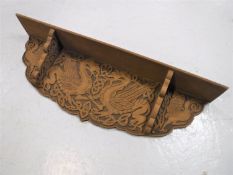 A carved oak wall shelf depicting dragons