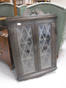 An oak double door wall mounted corner cabinet with leaded glass doors