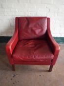 A twentieth century red leather armchair and footstool on rosewood legs