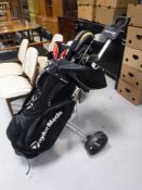A Taylor Made golf bag and a set of irons and drivers with folding stowaway golf cart