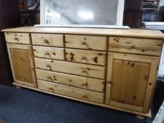 A contemporary pine sideboard with two cupboards and nine drawers
