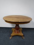 An antique mahogany oval pedestal on paw feet
