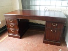 A contemporary mahogany finish twin pedestal writing desk with brass drop handles