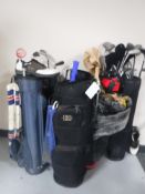 Six assorted golf bags containing clubs and drivers, folding golf trolley,