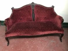 A Victorian mahogany framed settee upholstered in a maroon button brocade