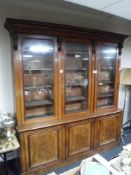 A Victorian mahogany triple door glazed bookcase fitted with cupboards beneath