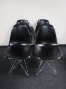 A set of four black plastic dining chairs on metal legs