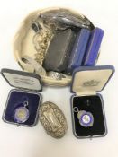 A brass tin containing silver purse, five silver sporting medals,