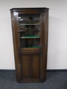 An oak glazed door corner cabinet