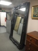 A ornate black framed free standing mirror,
